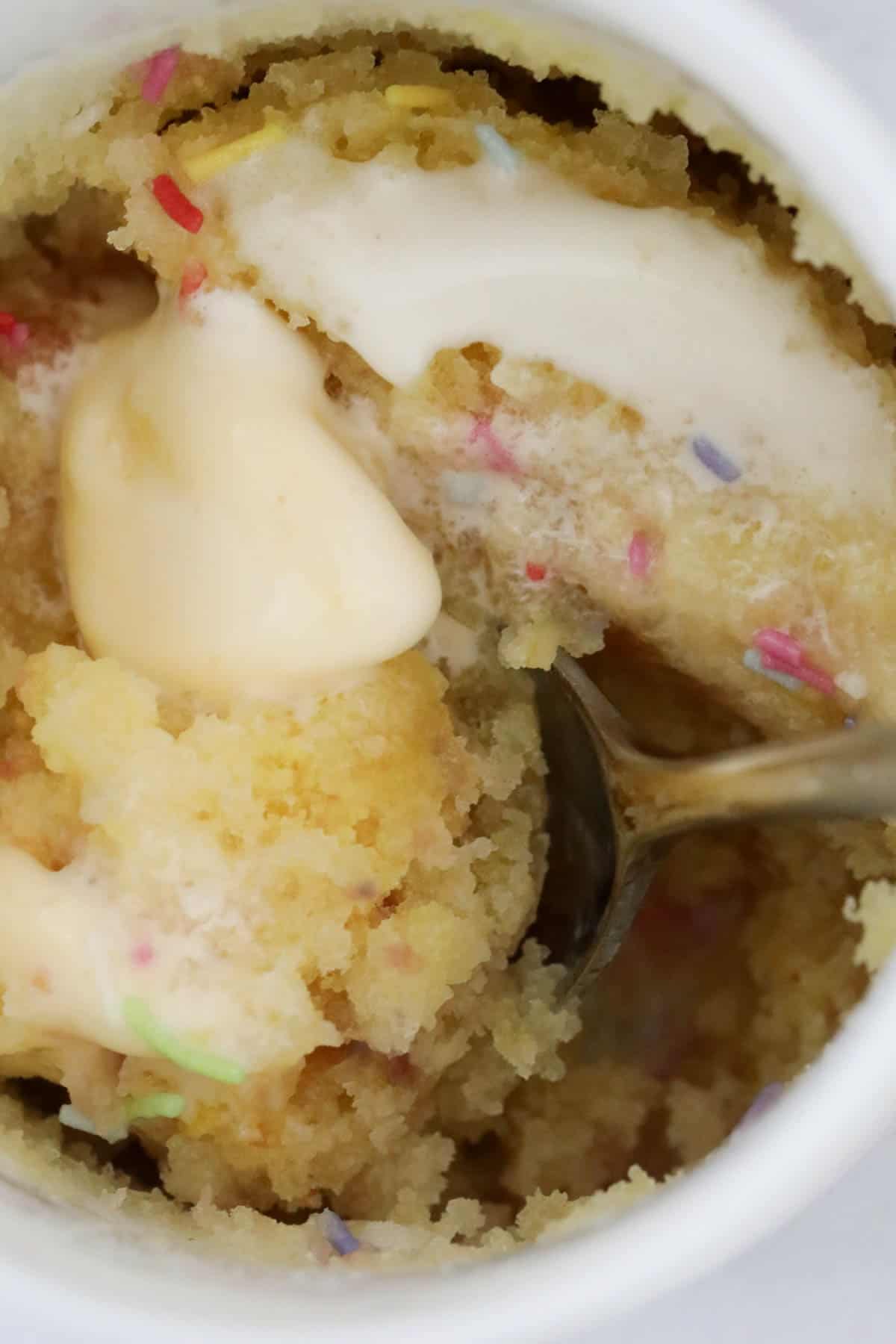 A close up of gluten free vanilla mug cake with ice cream and sprinkles.