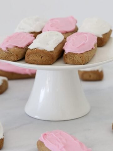 Pink and white icing on top of honey log biscuits.