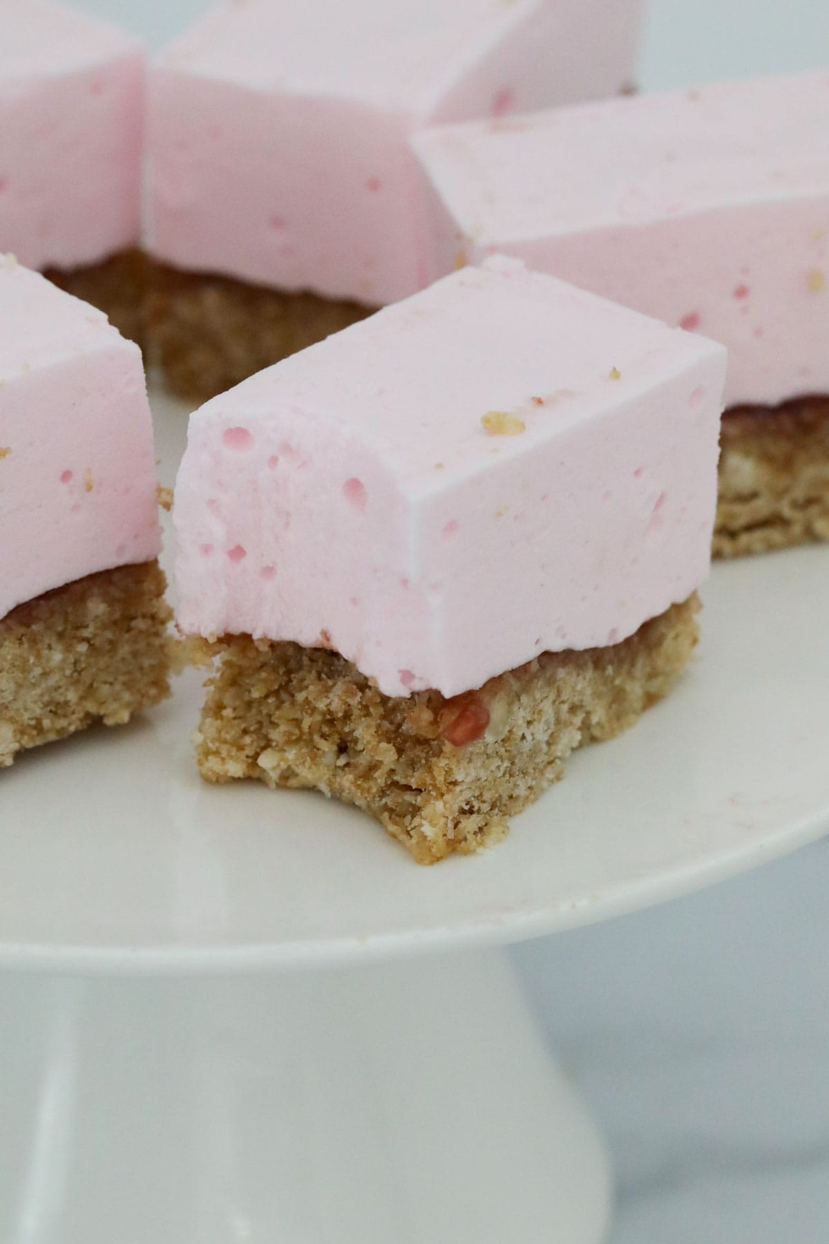 Pieces of marshmallow slice on a cake stand, with a bite taken out of one.