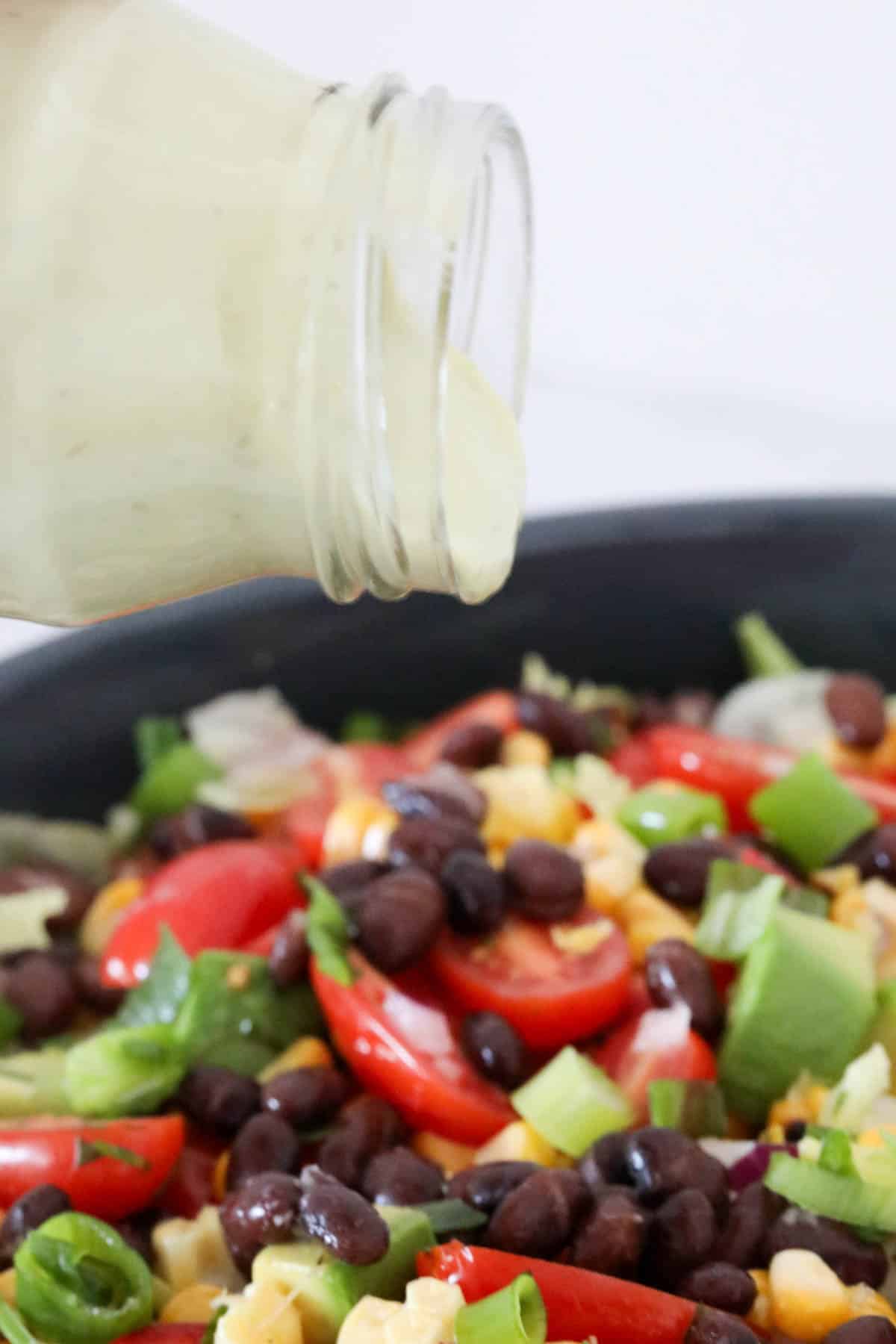 Avocado and lime salad dressing being poured over the mixed salad.