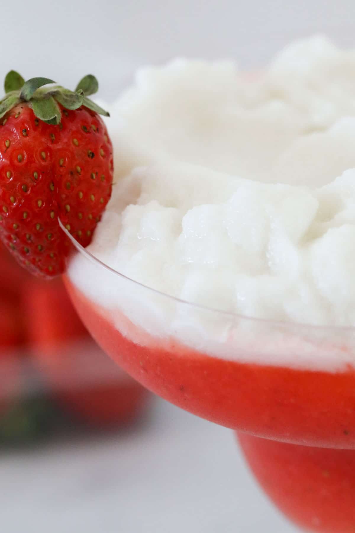 Close up of the cocktail in the stemmed cocktail glass served with a fresh strawberry on the side.