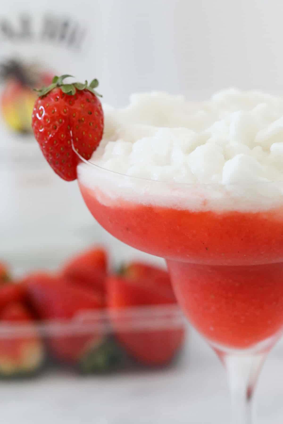 A Miami Vice cocktail in a glass, garnished with a fresh strawberry.