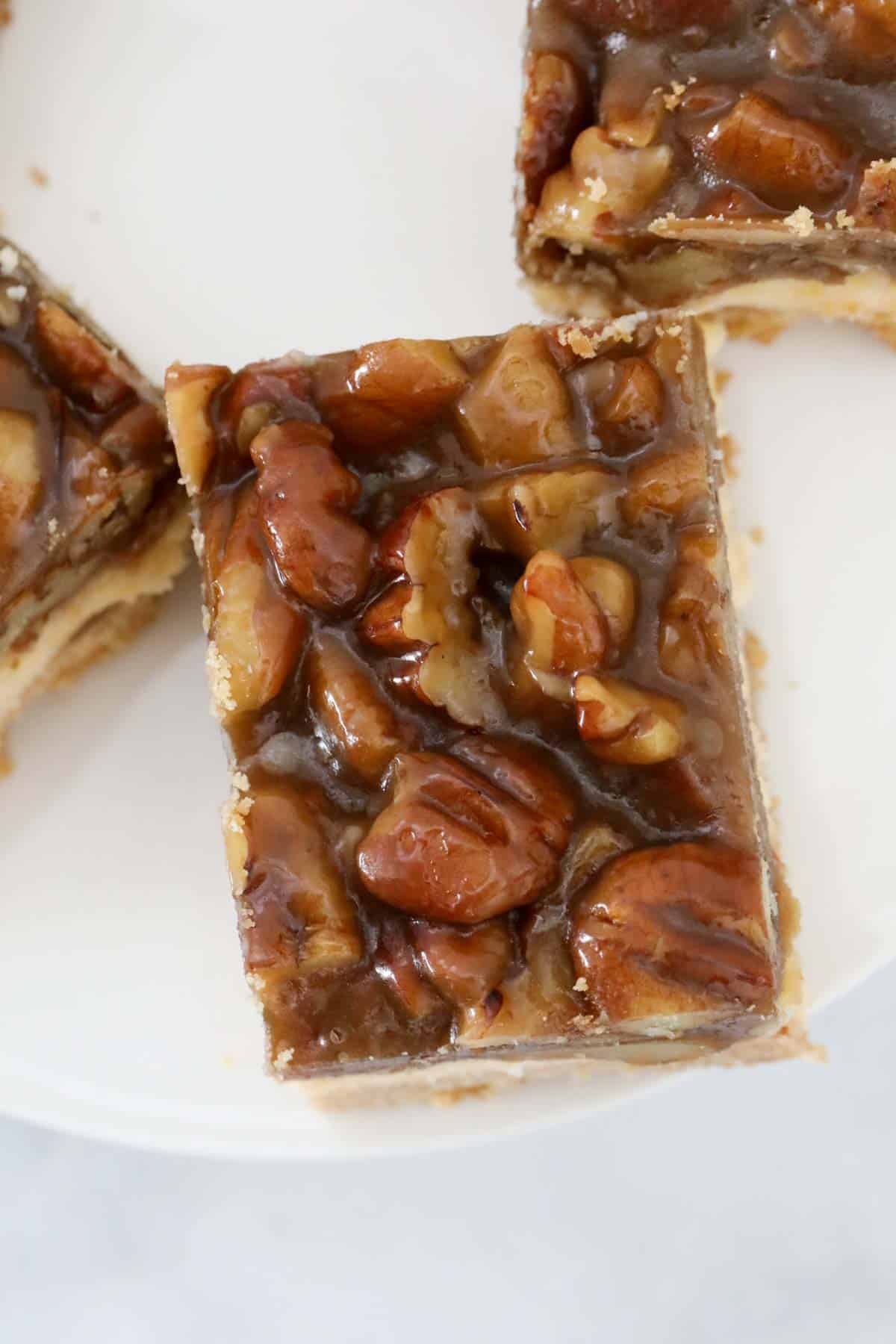 Overhead shot of the top of a slice of pecan pie cheesecake on white plate.