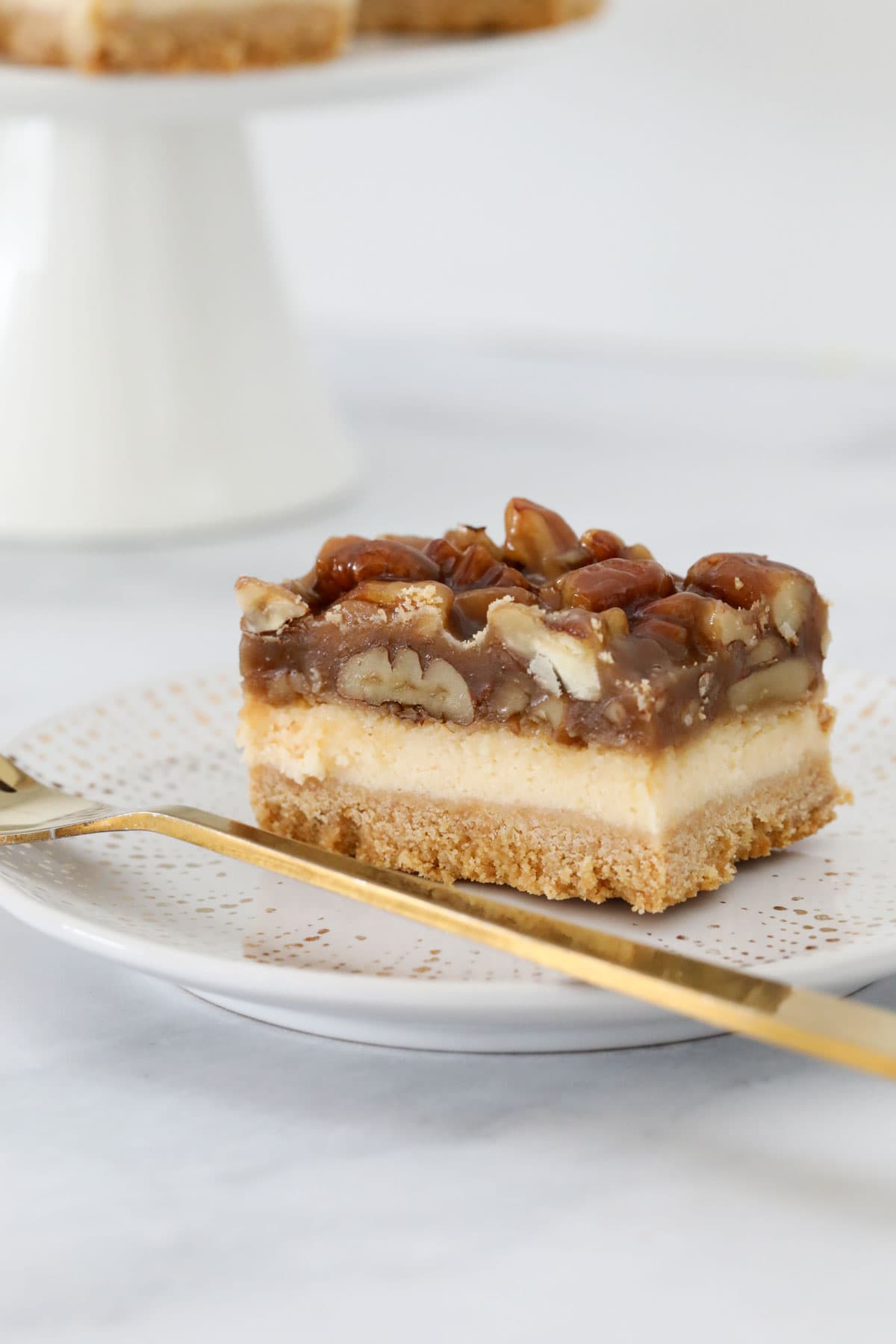 A serving of pecan pie cheesecake on a plate with a fork.