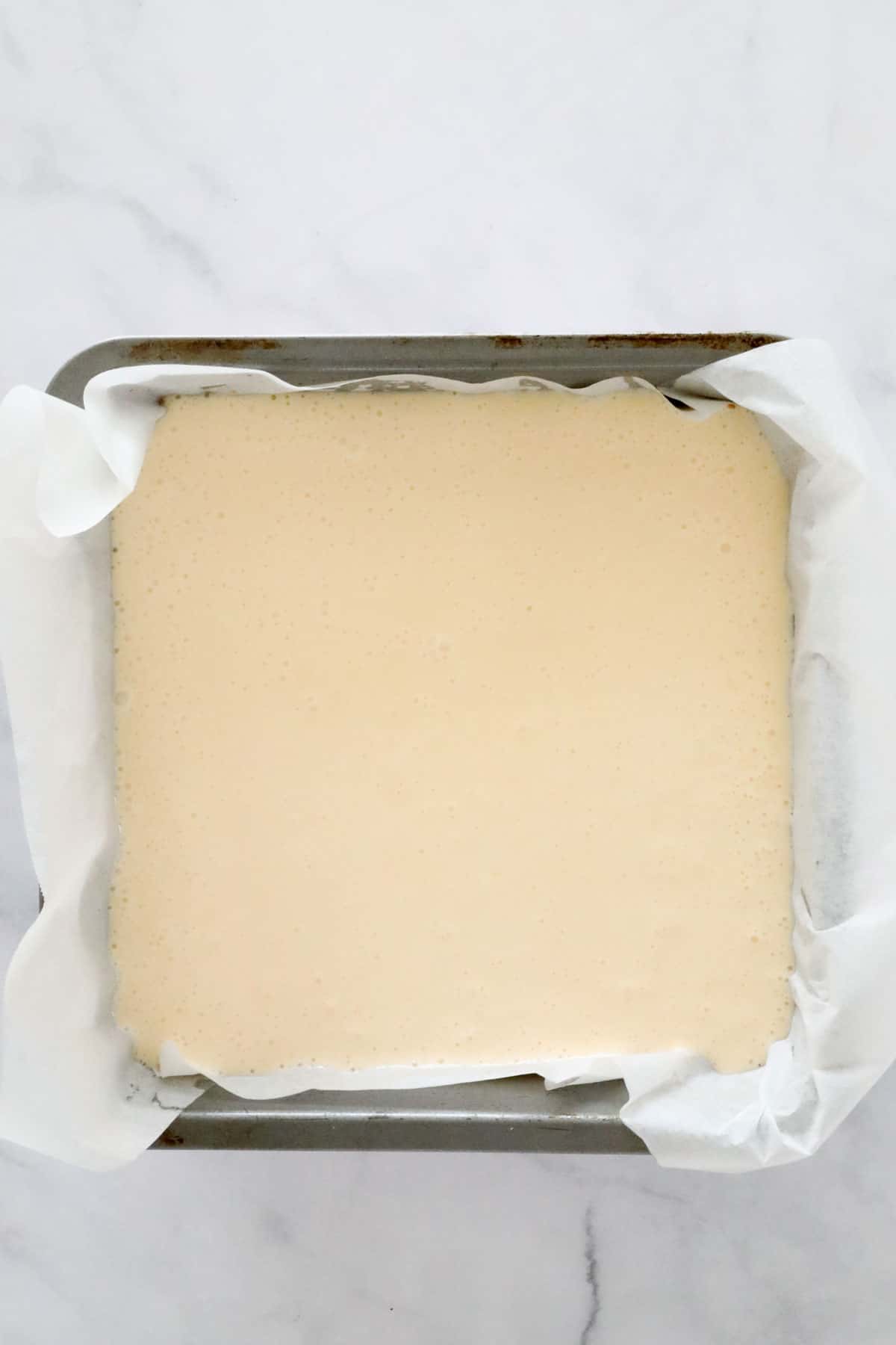 The vanilla cheesecake mixture poured in to the lined tin on top of the base.