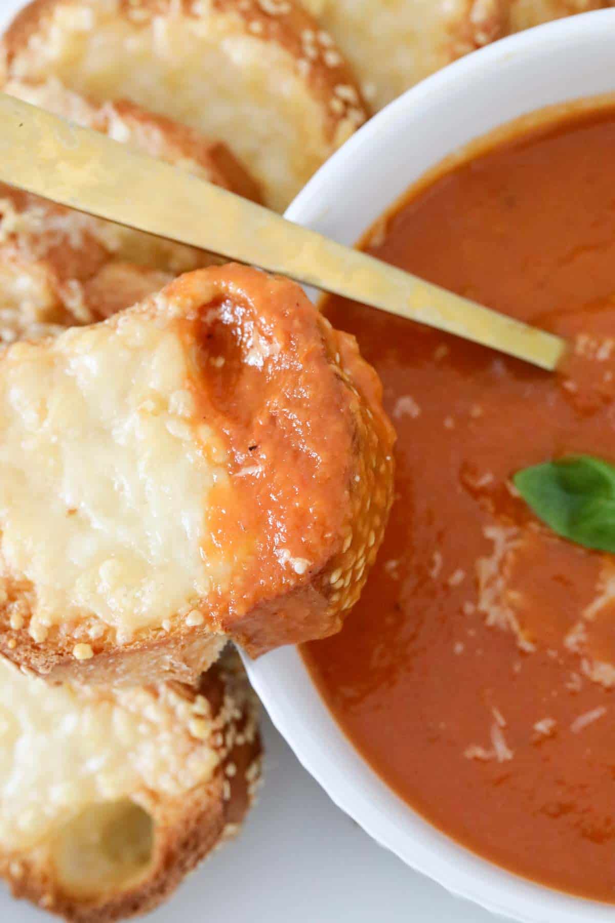 A bowl of roasted tomato soup served with a grilled cheese toastie on the side.