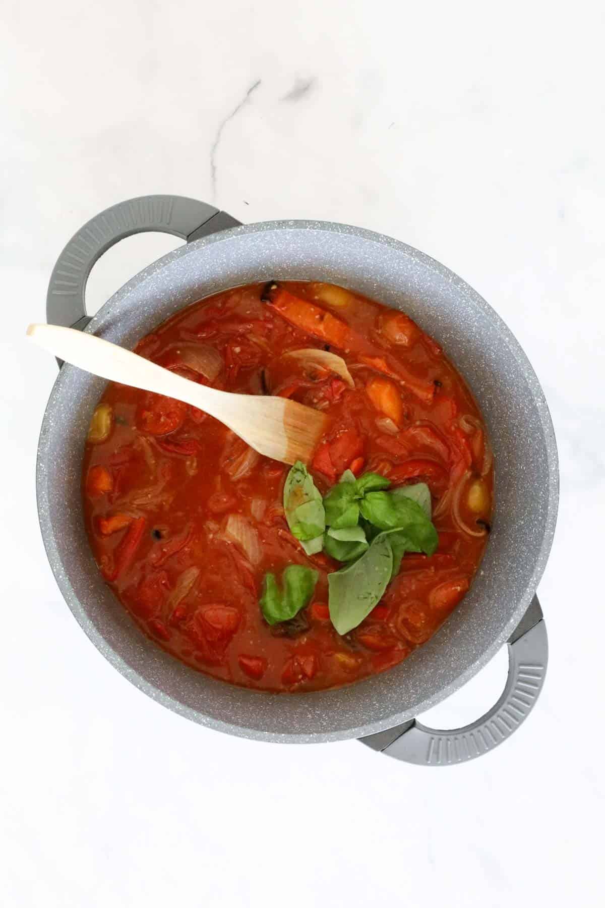 Fresh basil added to the soup in the saucepan.