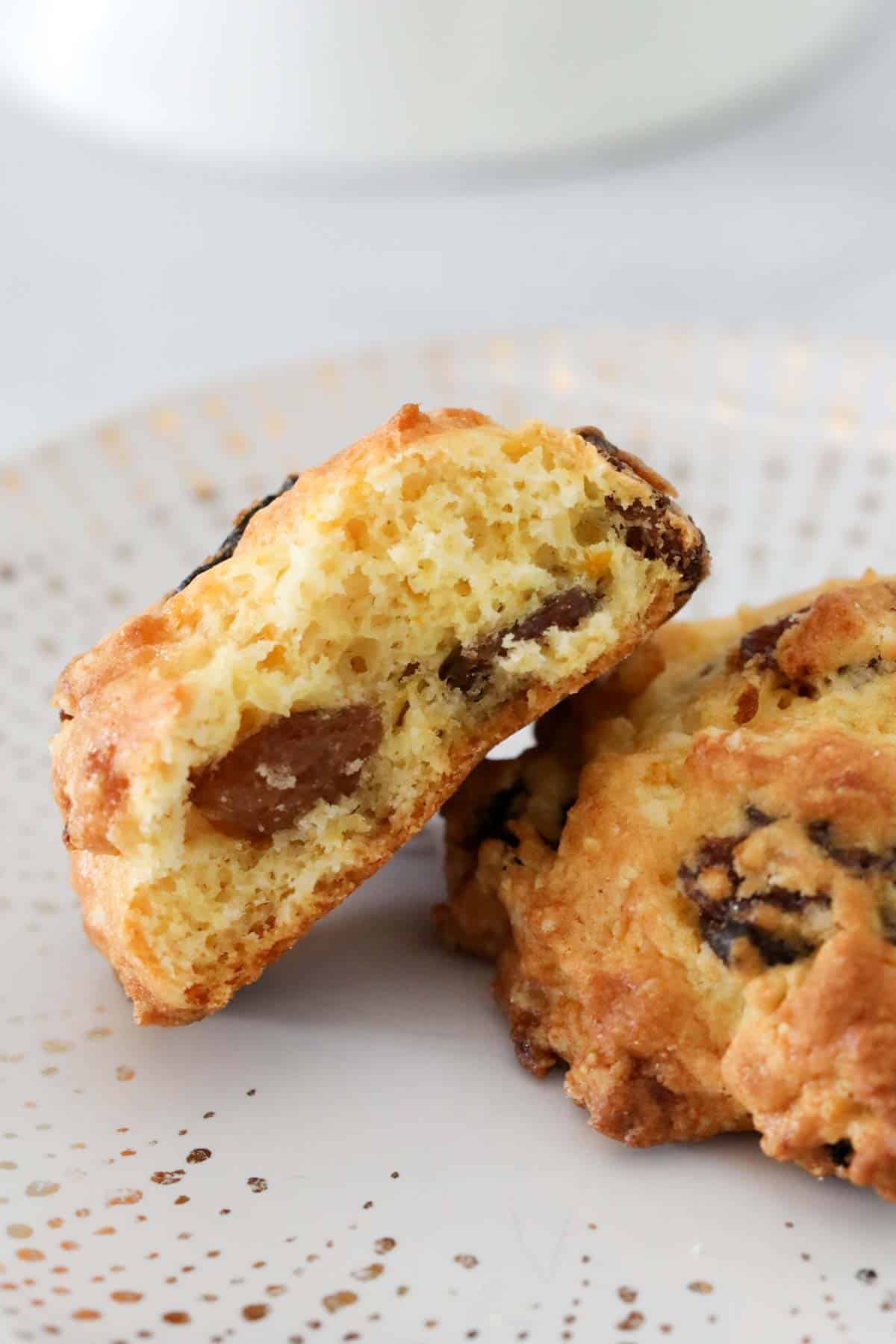 Close up of two rock cakes on a plate, one halved to show its light texture.