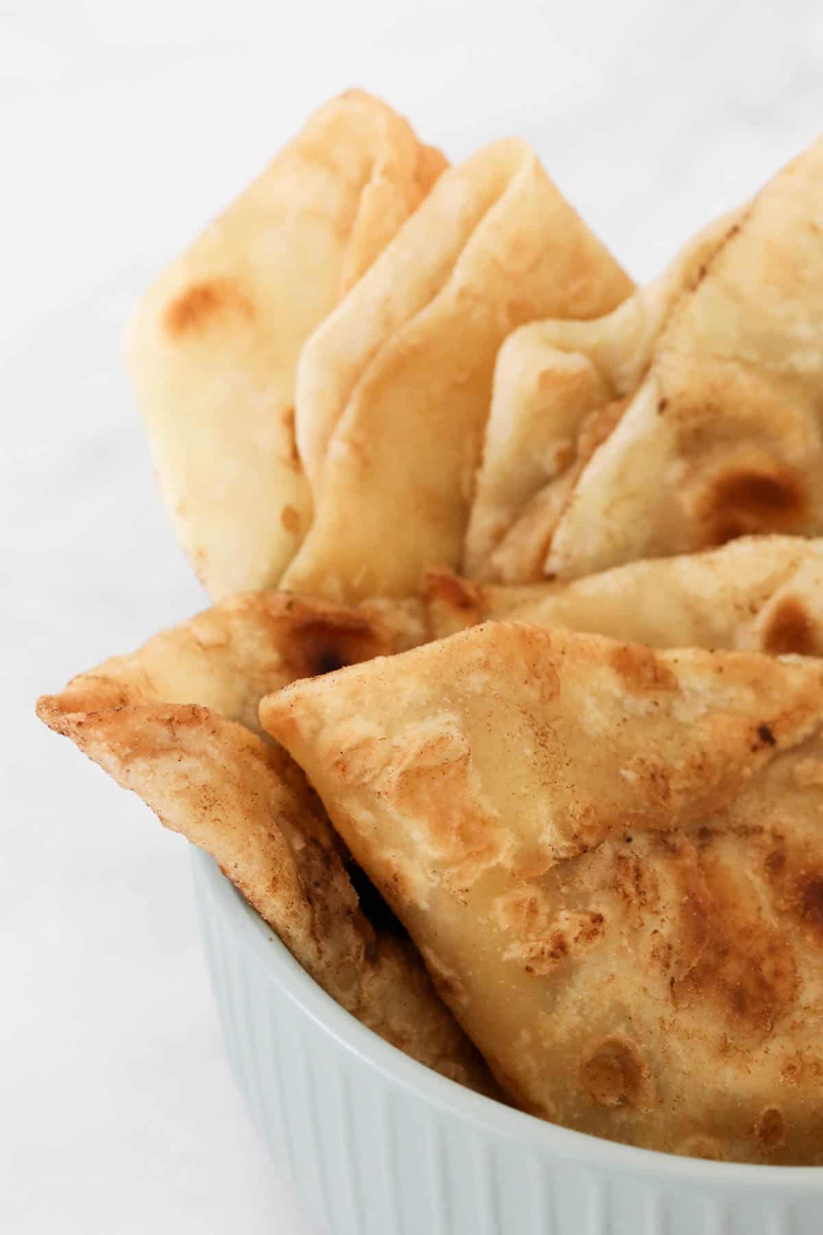 Close up of a bowl of stacked cooked roti bread.