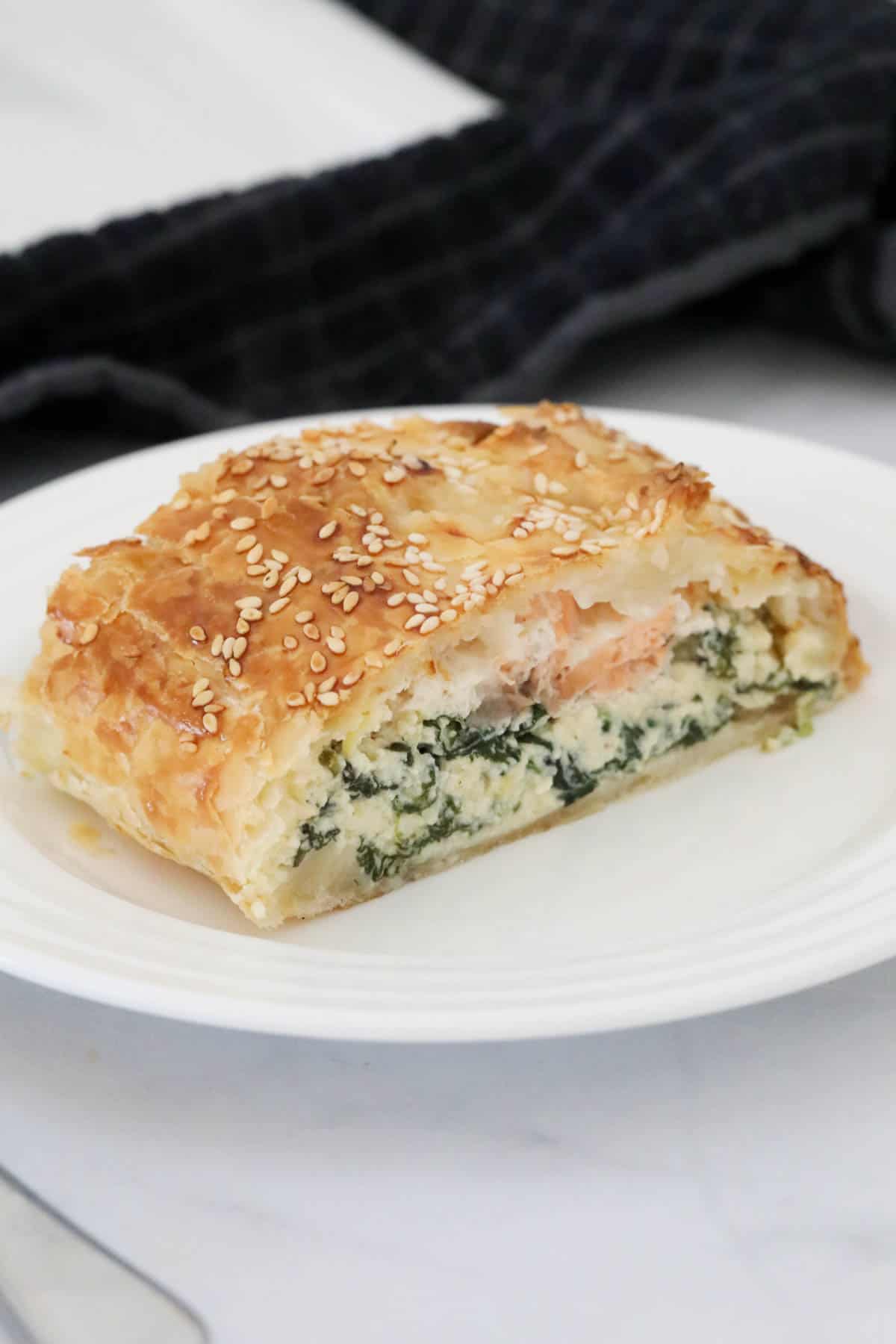 A slice of salmon puff pastry pie on a white plate.