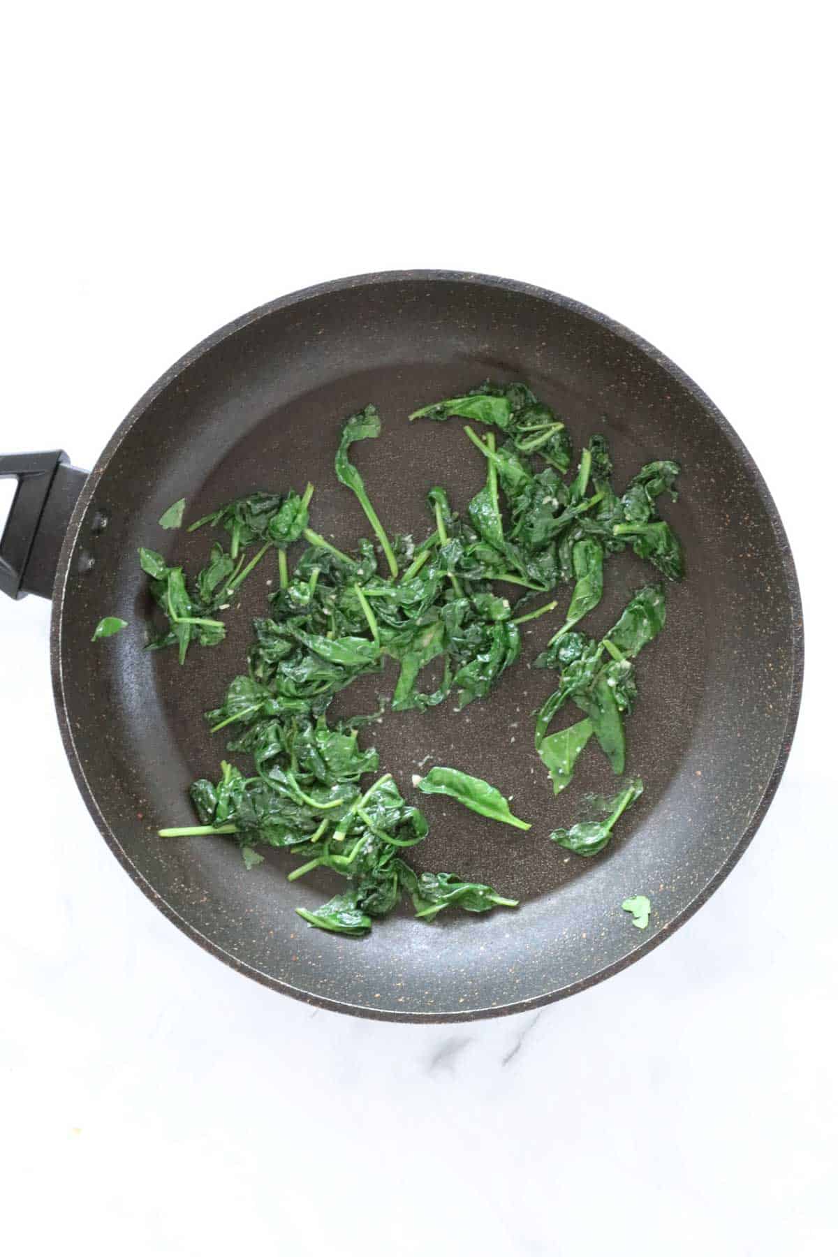 Wilted spinach in a frying pan.