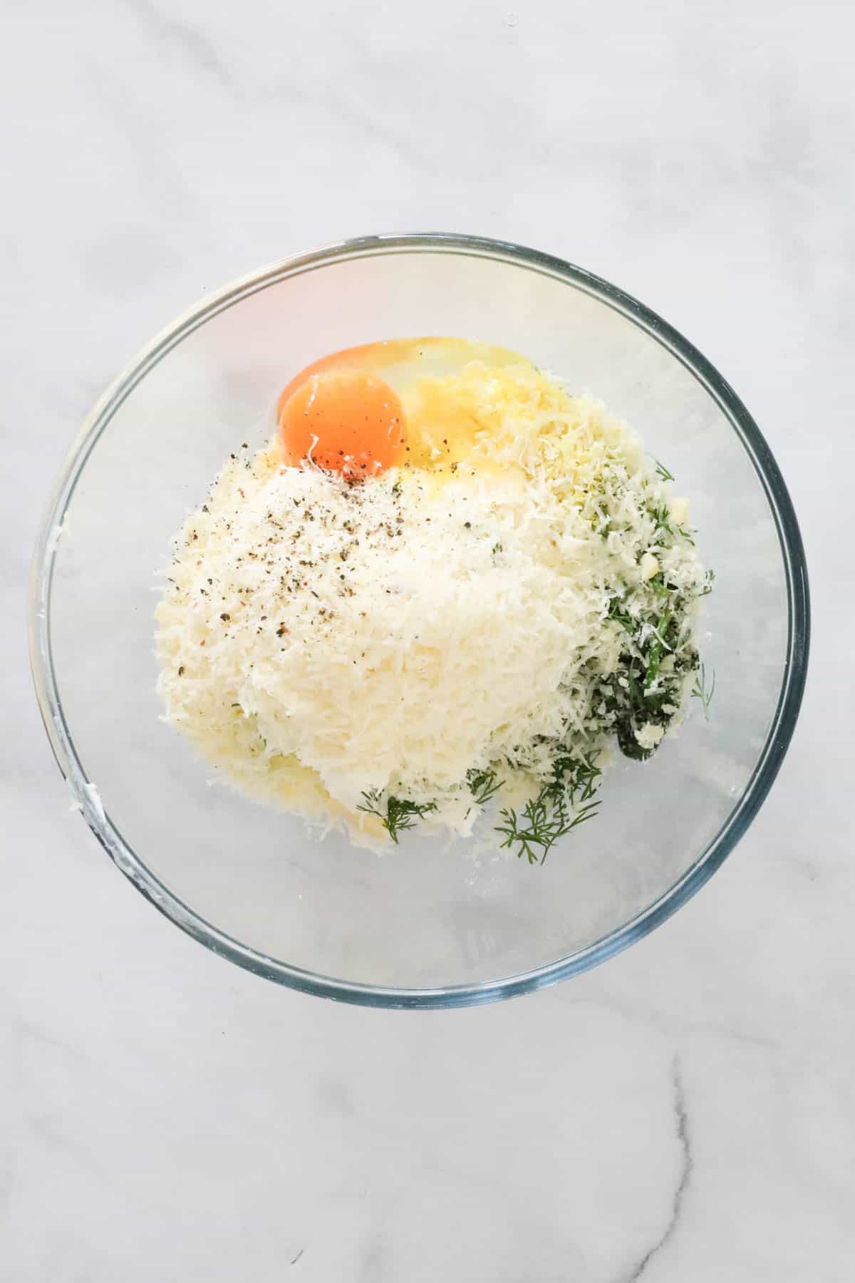 Ricotta, parmesan, egg, spinach, egg and seasonings in a bowl.