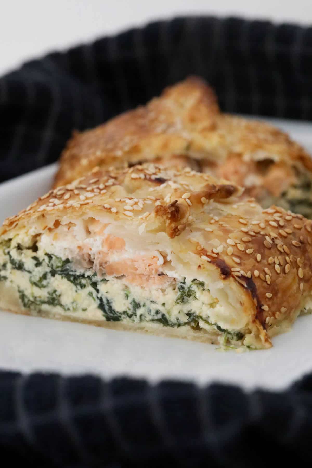 Two slices of baked salmon pie on baking paper.