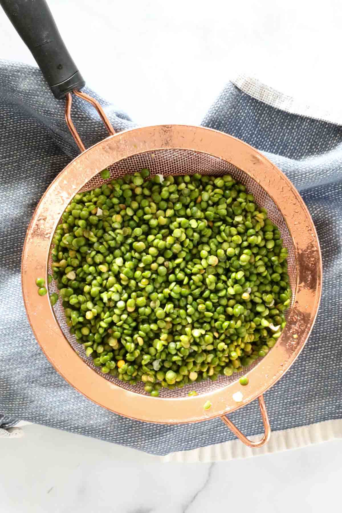 Rinsing split peas in a copper sieve.