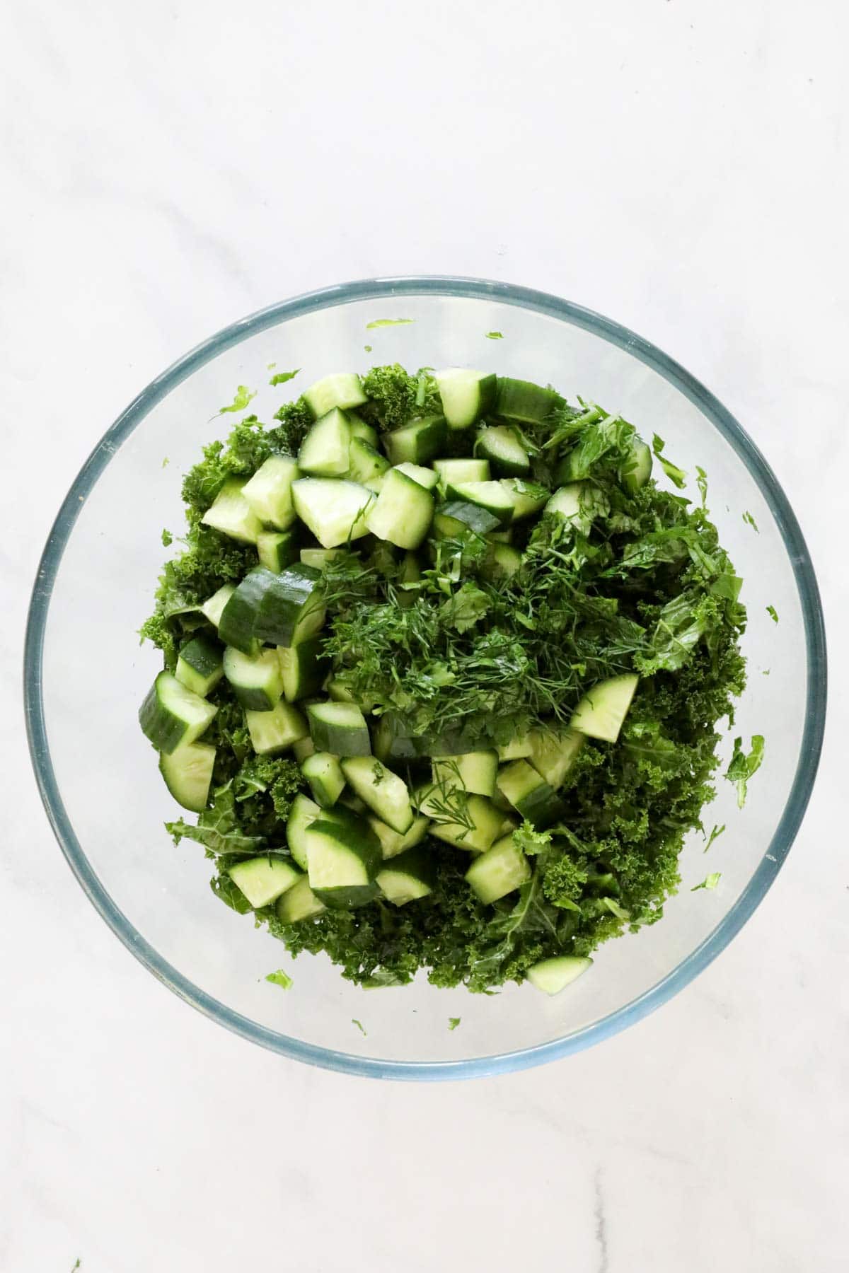 Chopped cucumber and herbs mixed with the massaged kale.