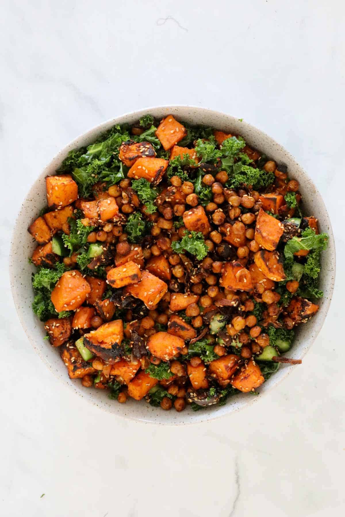 The roasted chickpeas and sweet potato added to the kale in a serving bowl.