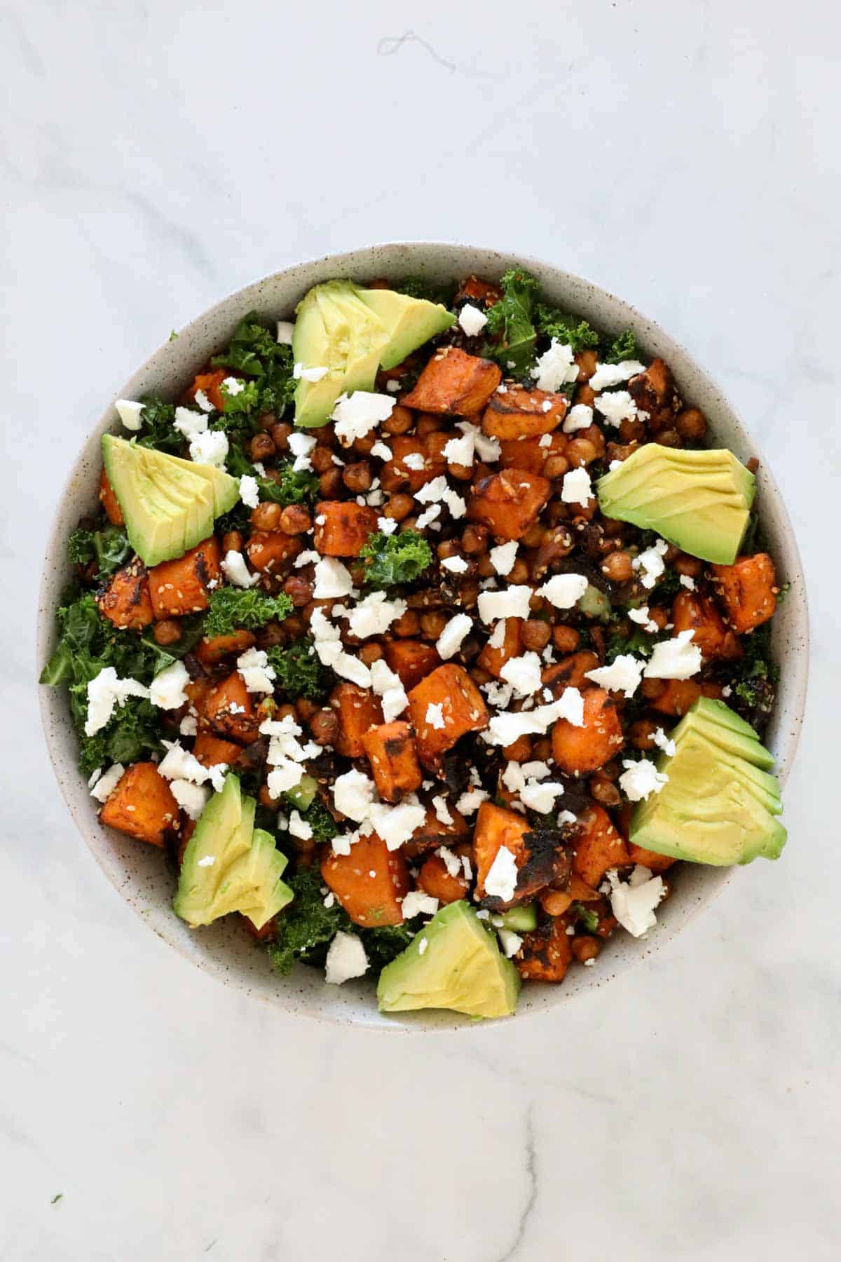 Sliced avocado and crumbled feta placed on top of the salad.