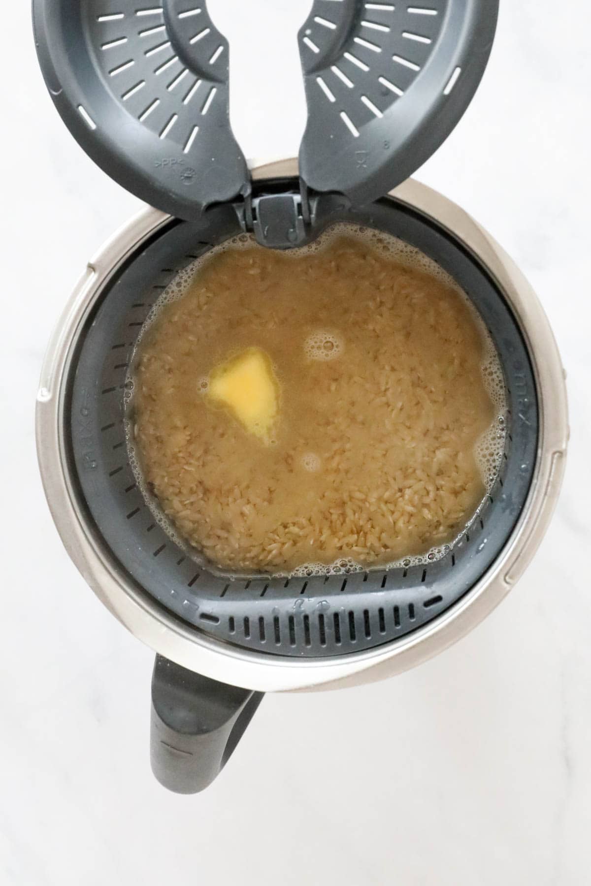 An overhead shot of water, rice and butter in a Thermomix.