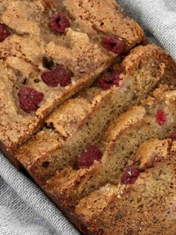 Slices of banana bread with raspberries on top.