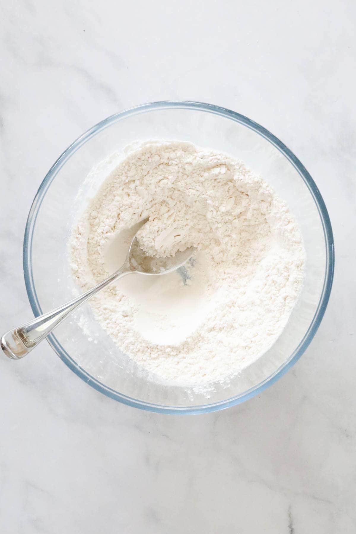 Flour and salt placed in a glass mixing bowl.