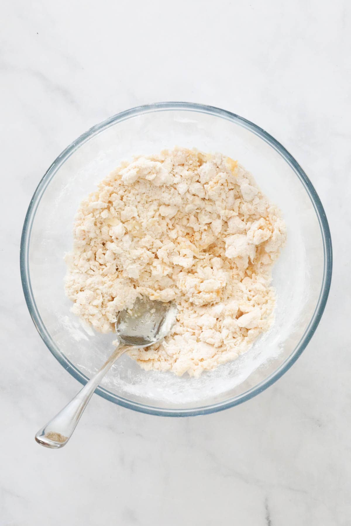 The egg and oil mixed through the flour to make a lumpy mixture in a glass bowl.