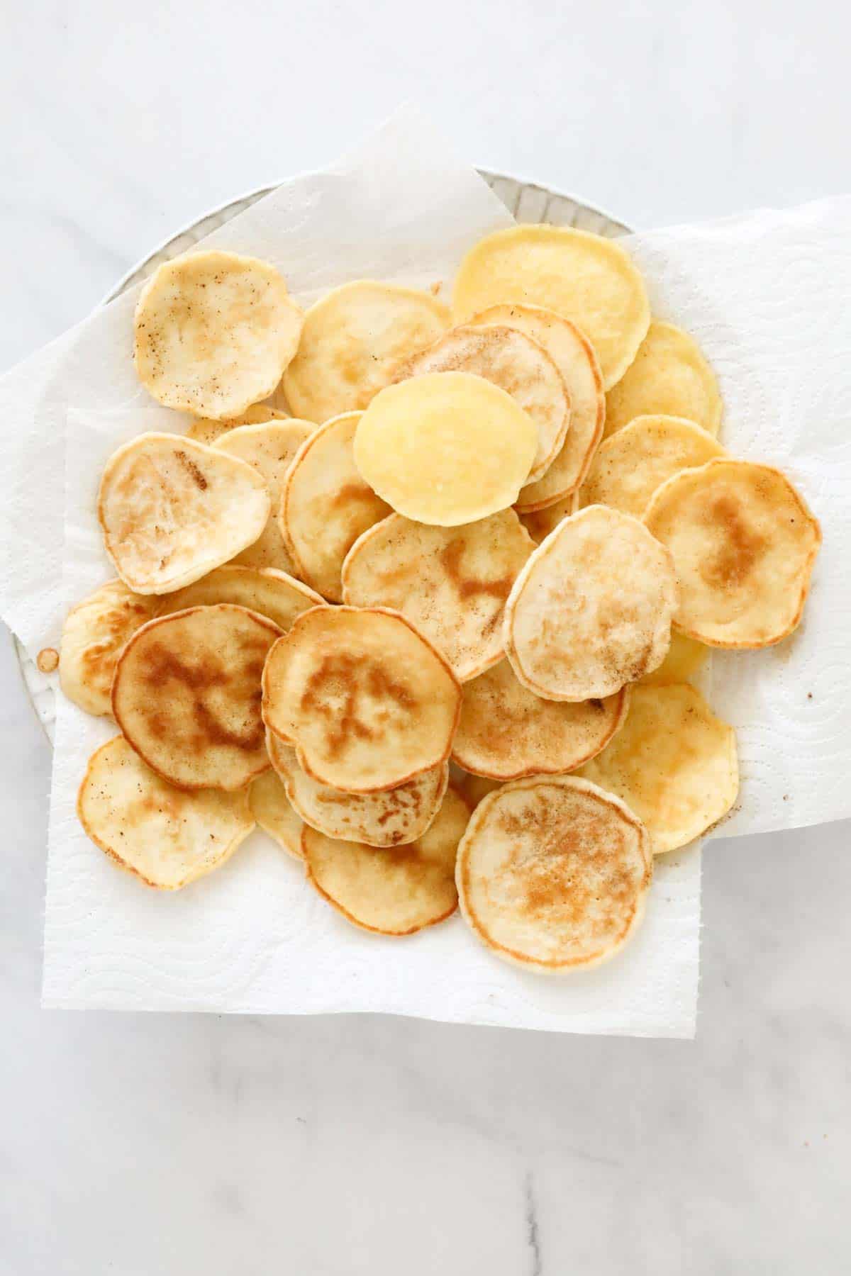 A pile of cooked blinis placed on paper towel.