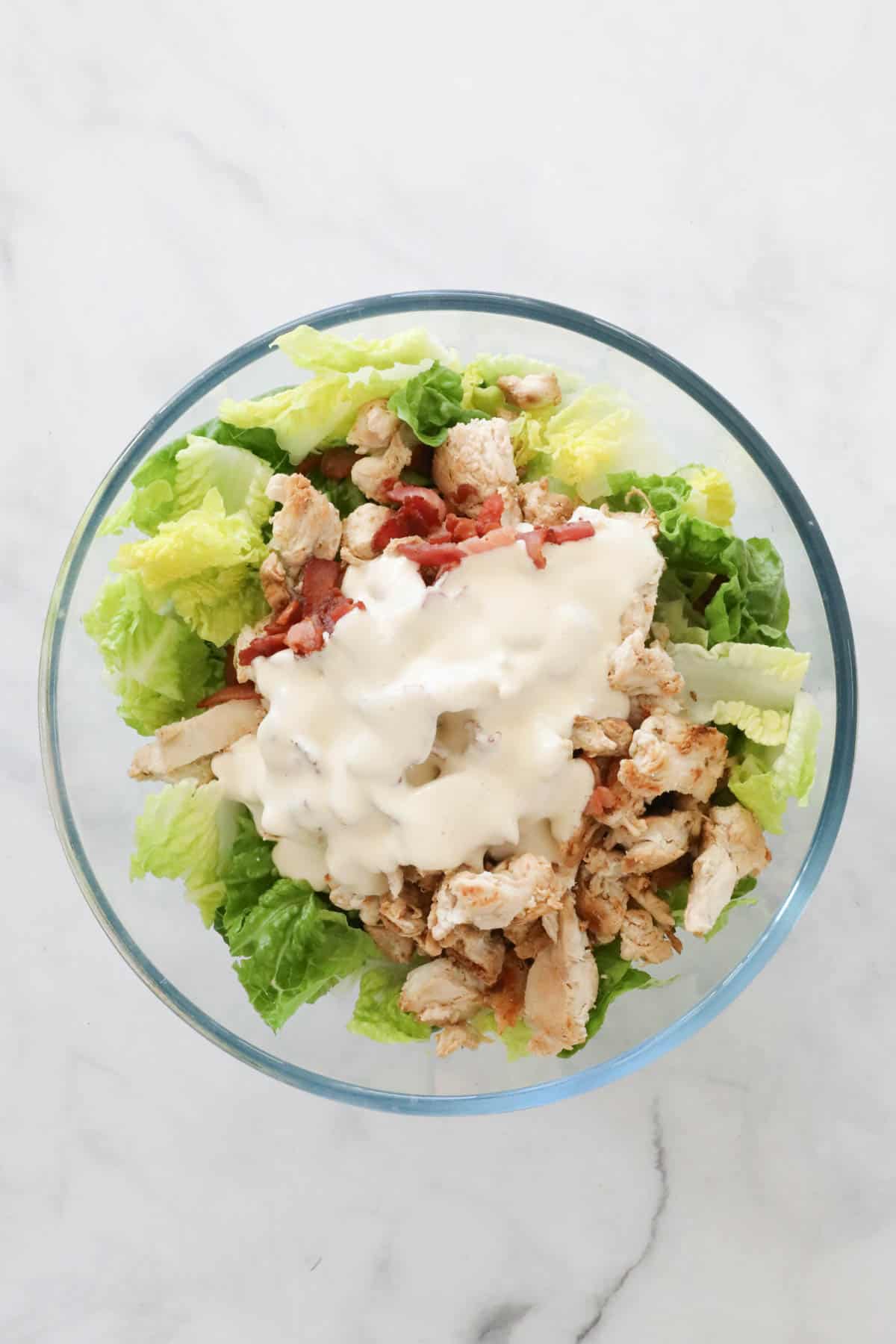 The Caesar dressing poured over the chicken, bacon and cos lettuce.