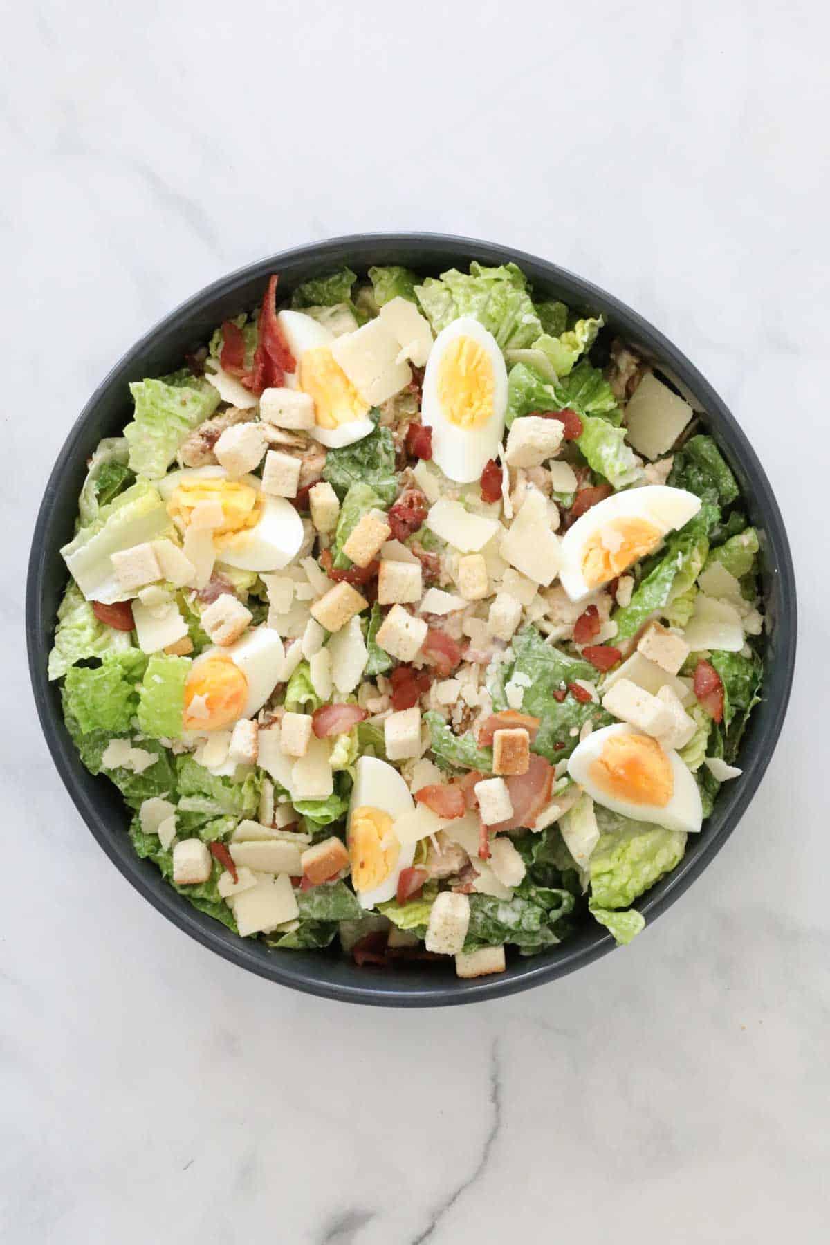 Caesar salad topped with quartered hard boiled eggs and croutons.