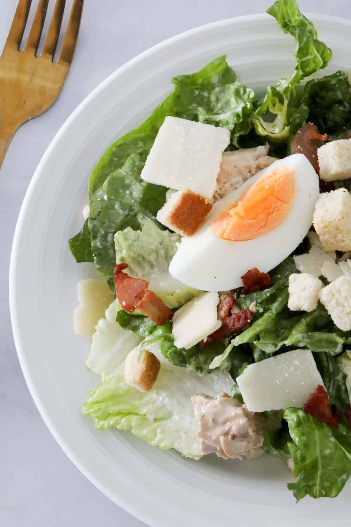 A portion of chicken Caesar salad served on a white plate.