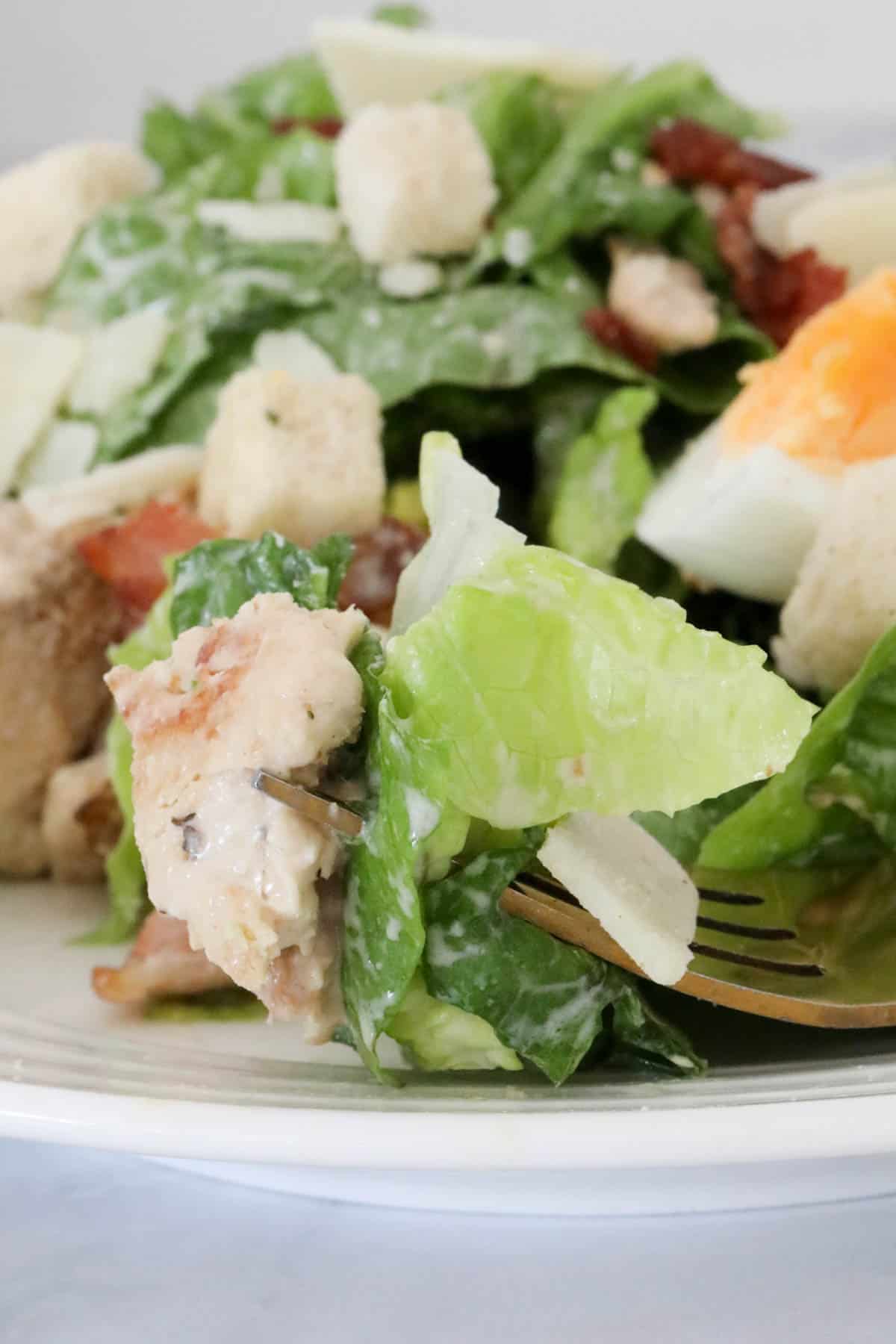 A forkful of creamy cos lettuce salad with chicken.