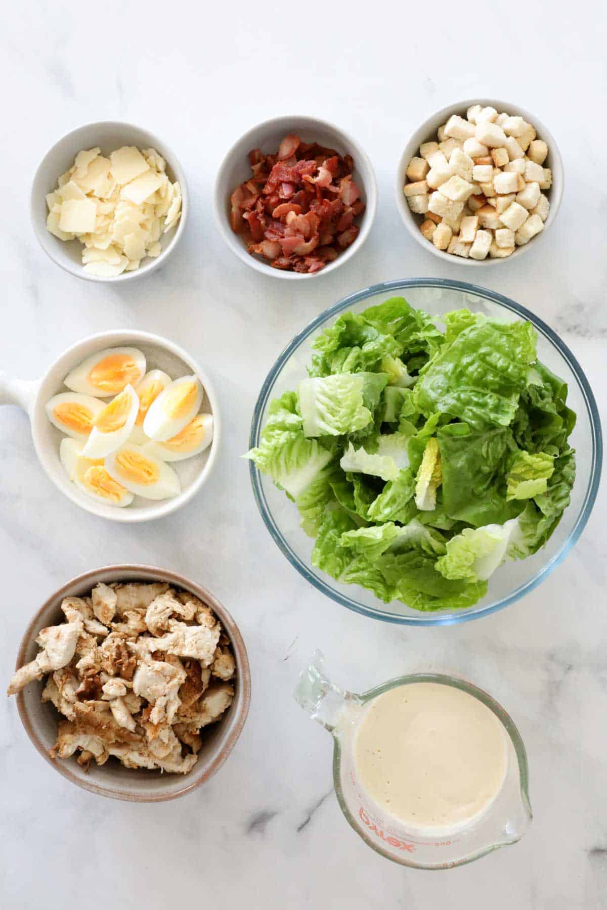 Ingredients needed to make the Caesar salad weighed out and placed in individual bowls.