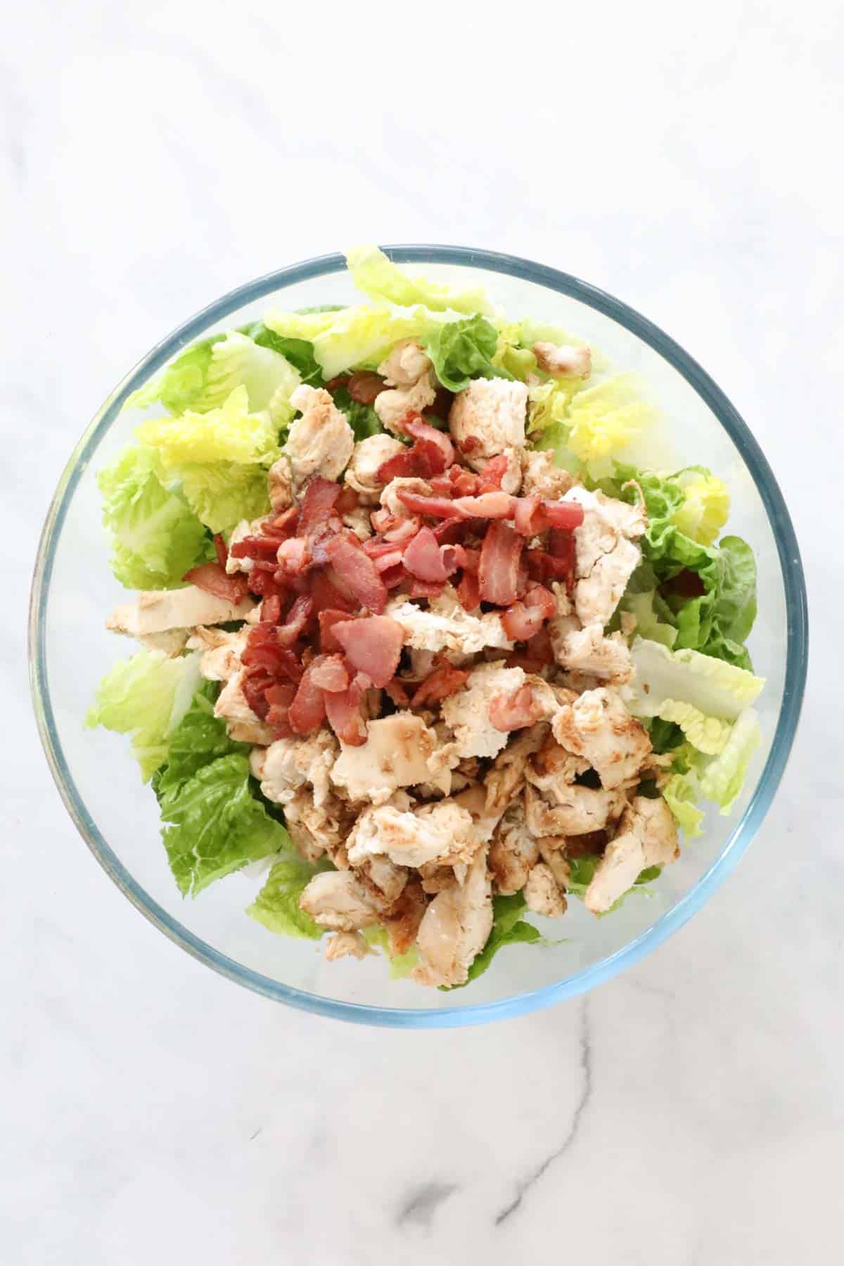 Cooked chicken and bacon in a large mixing bowl with the cos lettuce.