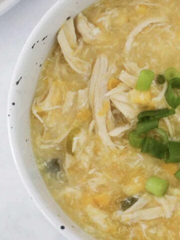 An overhead shot of a bowl of chicken and corn soup.