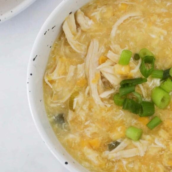 An overhead shot of a bowl of chicken and corn soup.