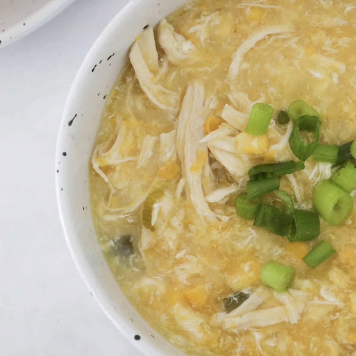 An overhead shot of a bowl of chicken and corn soup.