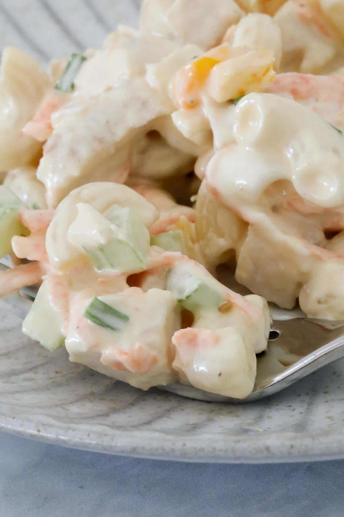 Close up of a mouthful of chicken salad on a fork.