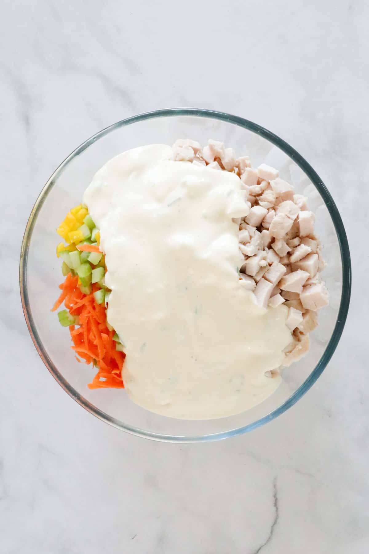 Dressing poured over the salad ingredients in the bowl.