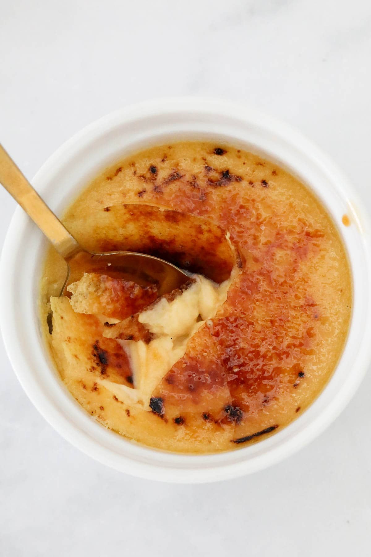 An overhead shot of a ramekin of creme brulee with a spoon resting in it.