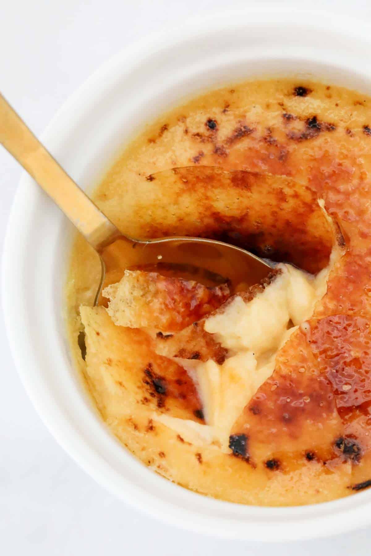 Close up of a spoon breaking the sugar top of the creme brûlée.