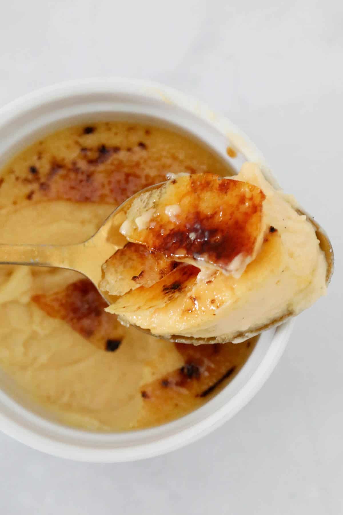 Overhead view of a spoonful of creme brûlée to show the crunchy sugar top and creamy set custard below.