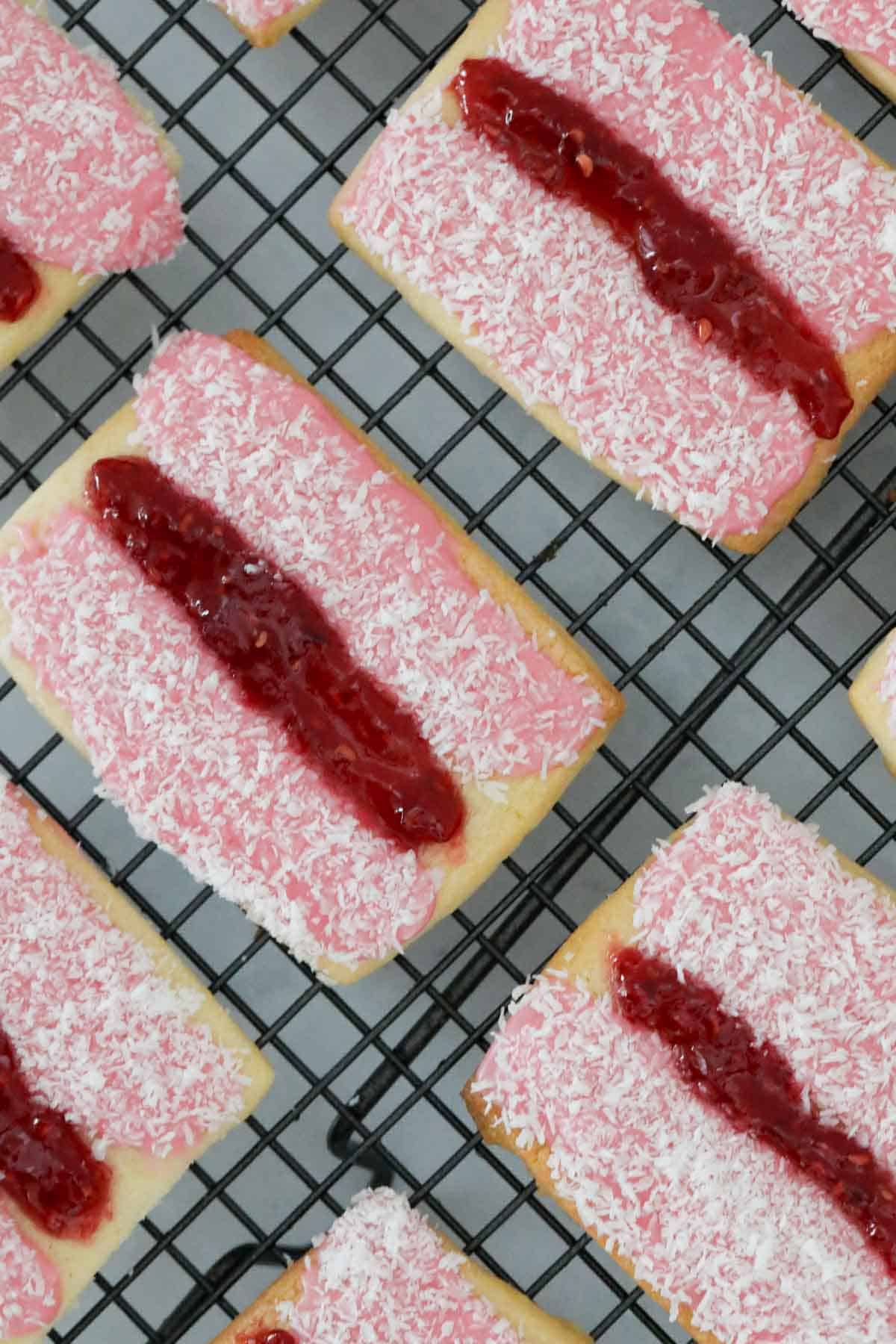 A number of iced vovo biscuits on a wire cooling rack.