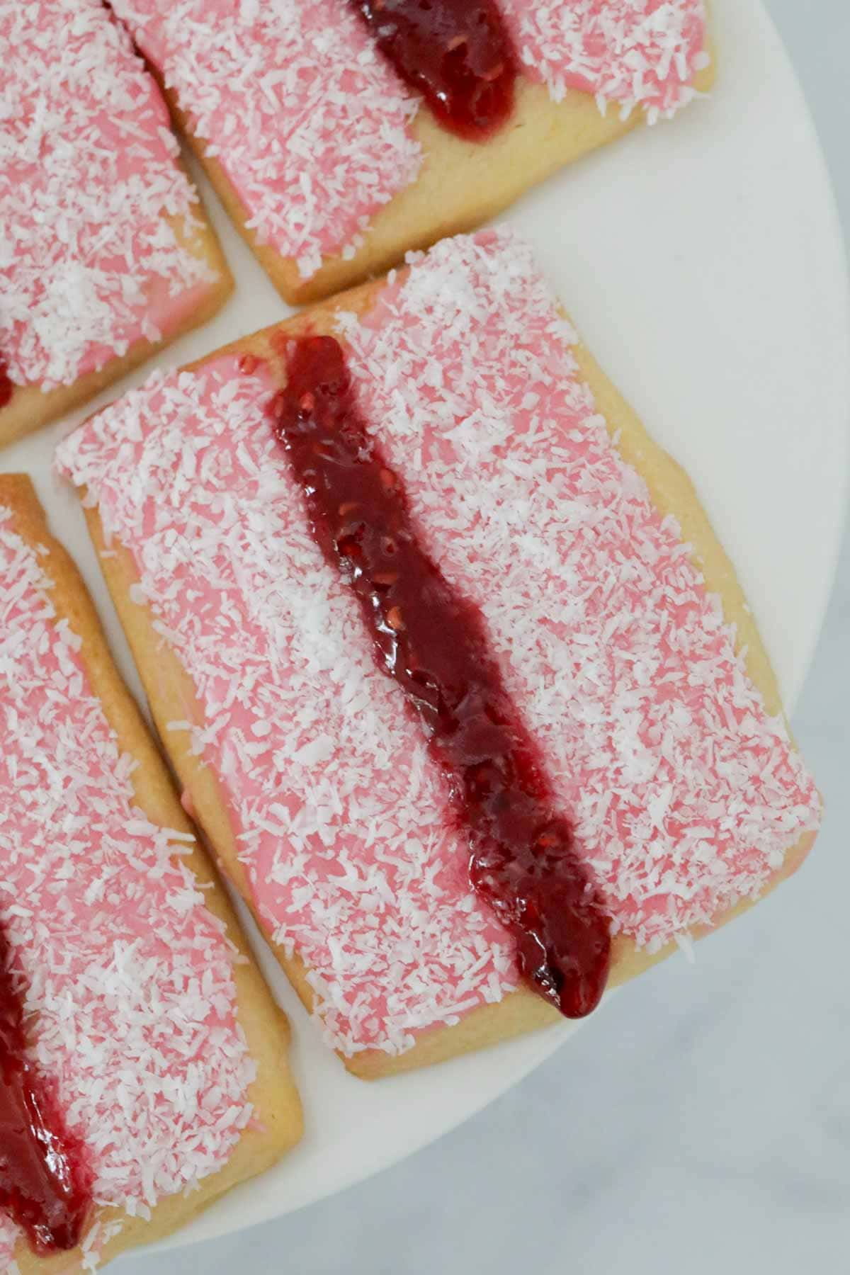 Close up of an iced vovo biscuit on a white cake stand.