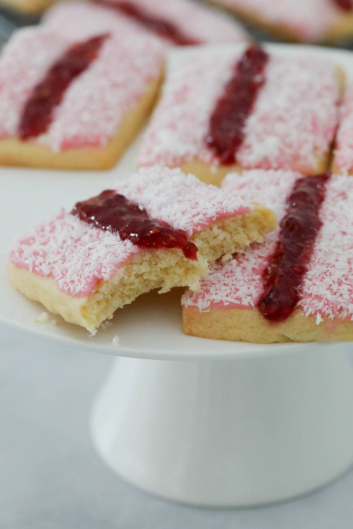 A close up of sweet cookies on a white cake stand.