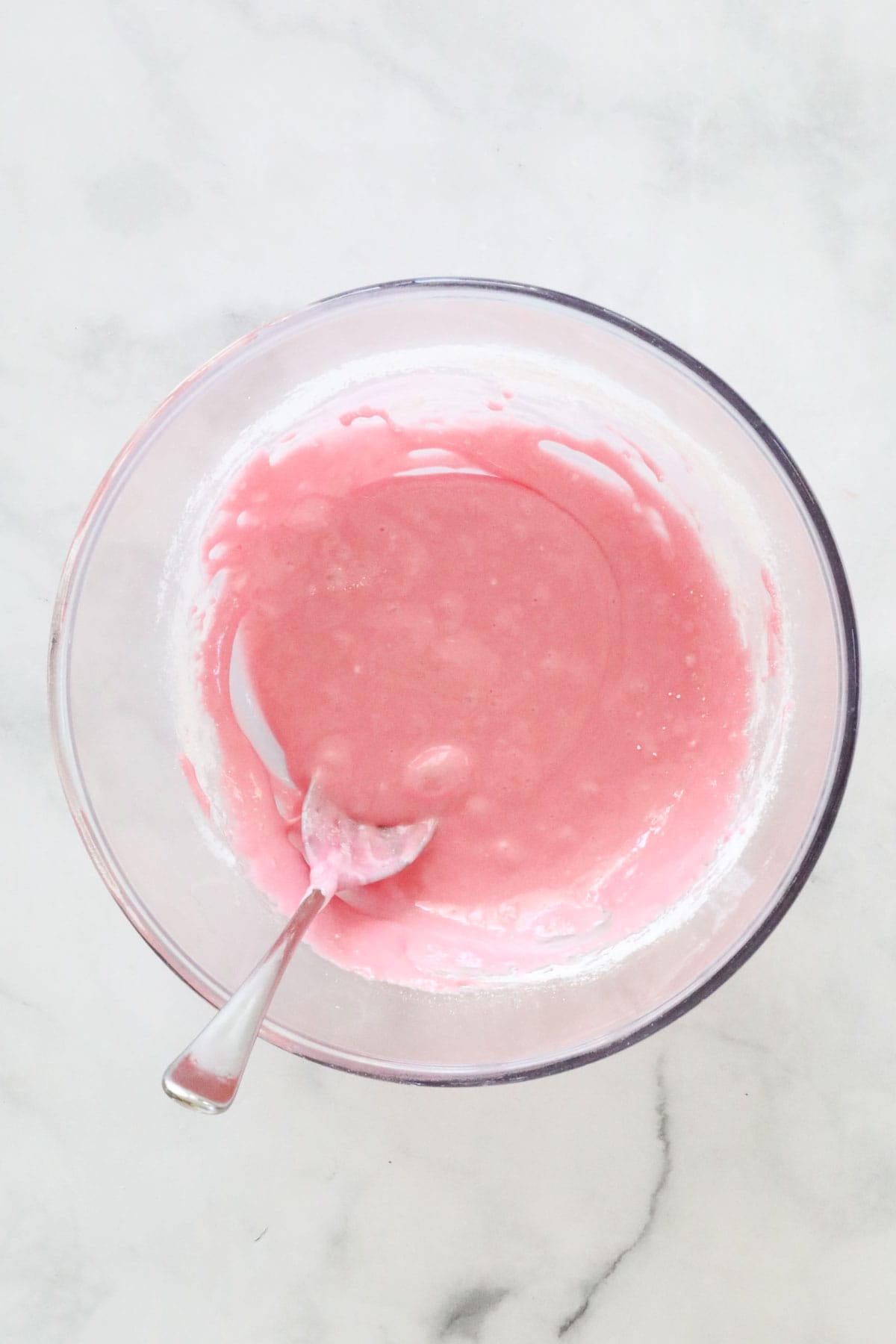 The smooth marshmallow mixture in a glass bowl with a metal spoon.