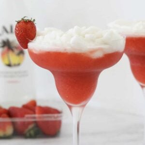 A cocktail glass layered with a frozen strawberry daiquiri and a pina colada.