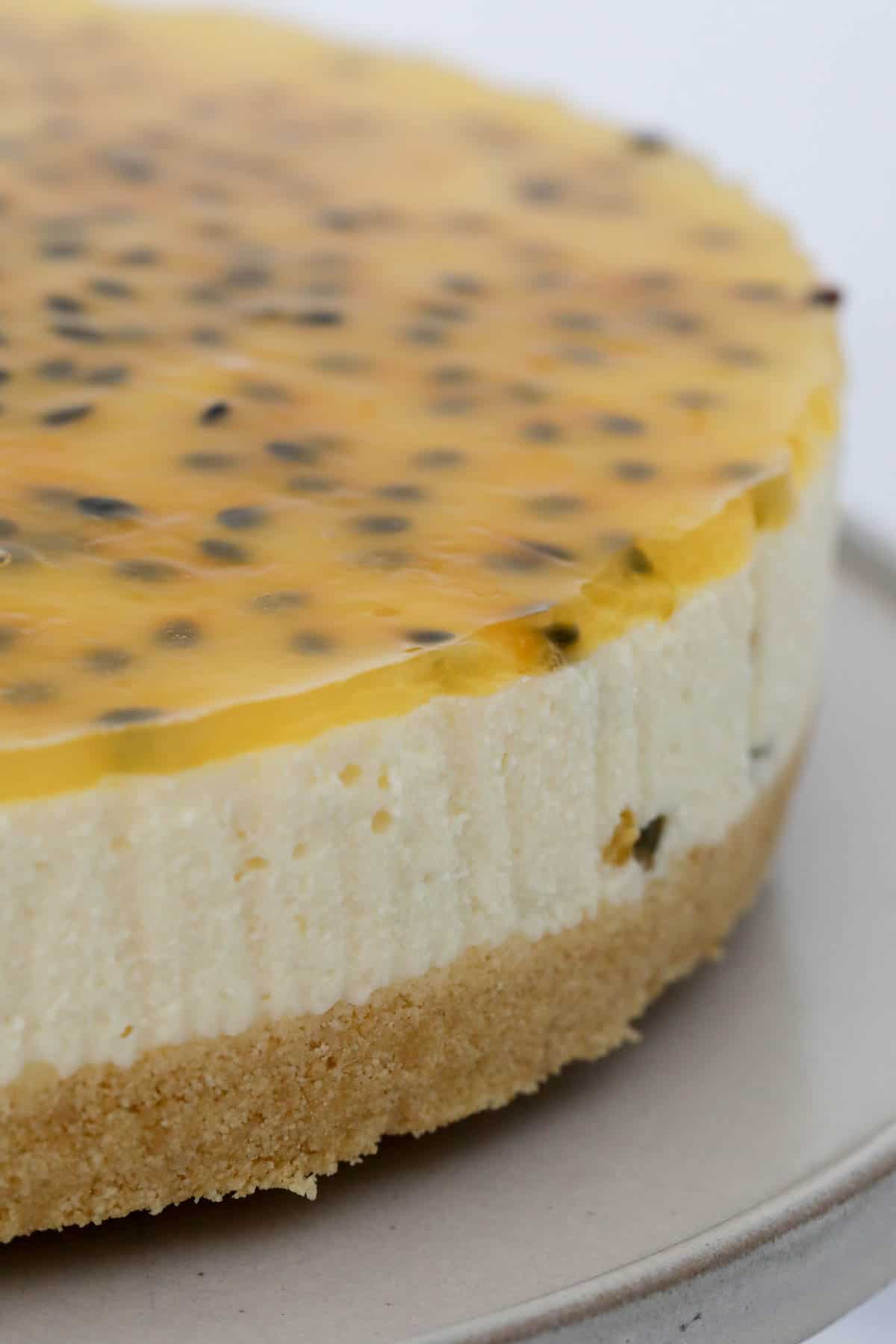 Close up of the set cheesecake with a passionfruit jelly topping, on a cake stand.