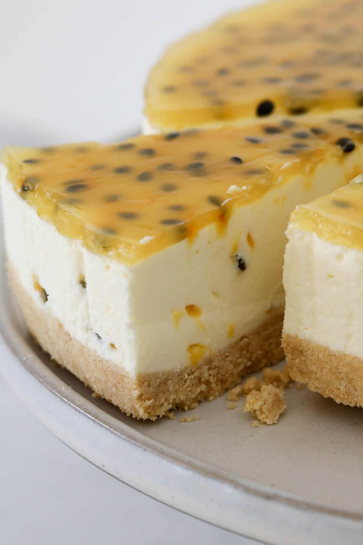 Passionfruit cheesecake with a slice slightly pulled out to show the cheesecake layers.