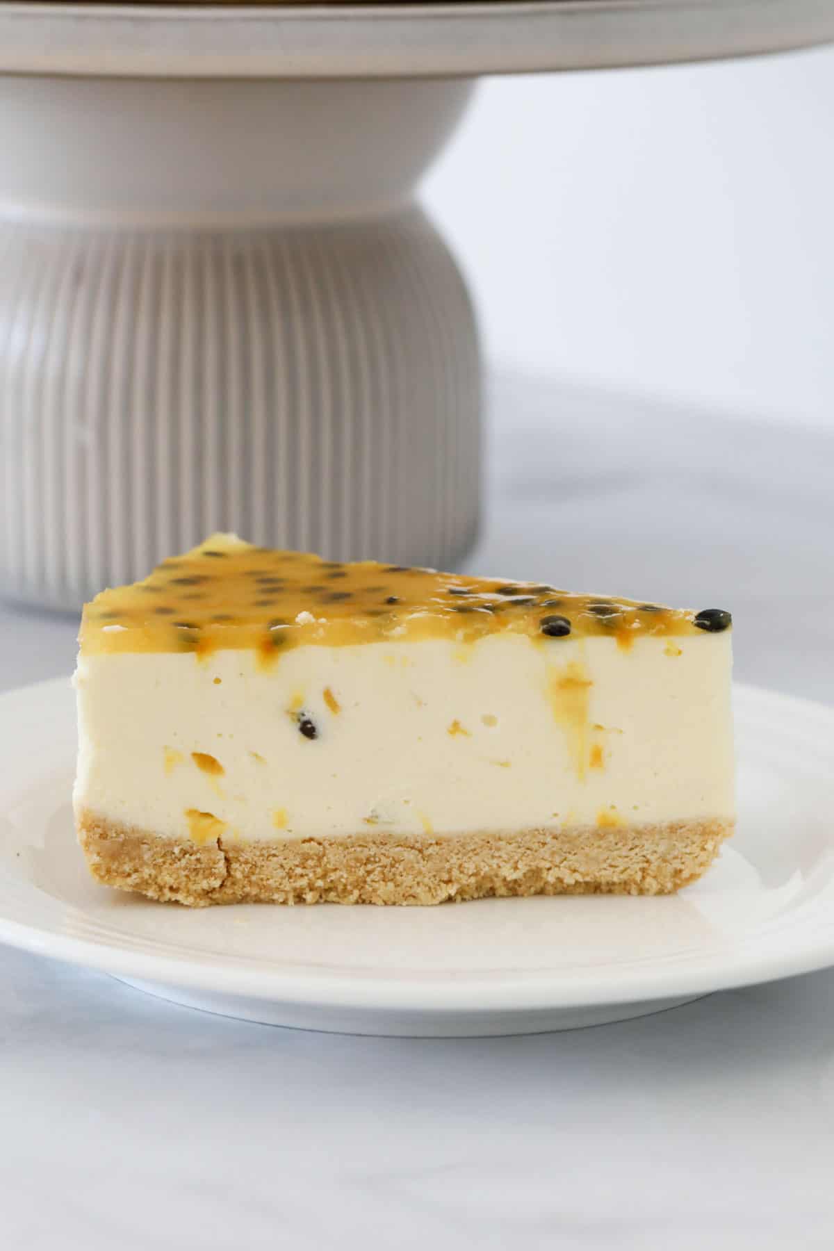 A wedge of layered passionfruit cheesecake served on a plate.