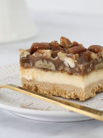 A piece of vanilla cheesecake topped with a caramel pecan layer.