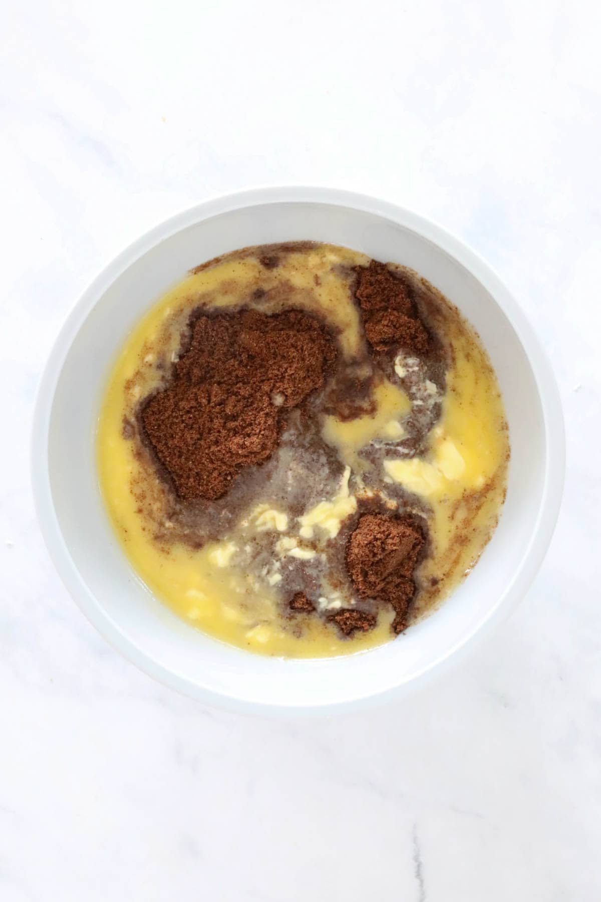 Crushed chocolate biscuits and melted butter in a bowl.